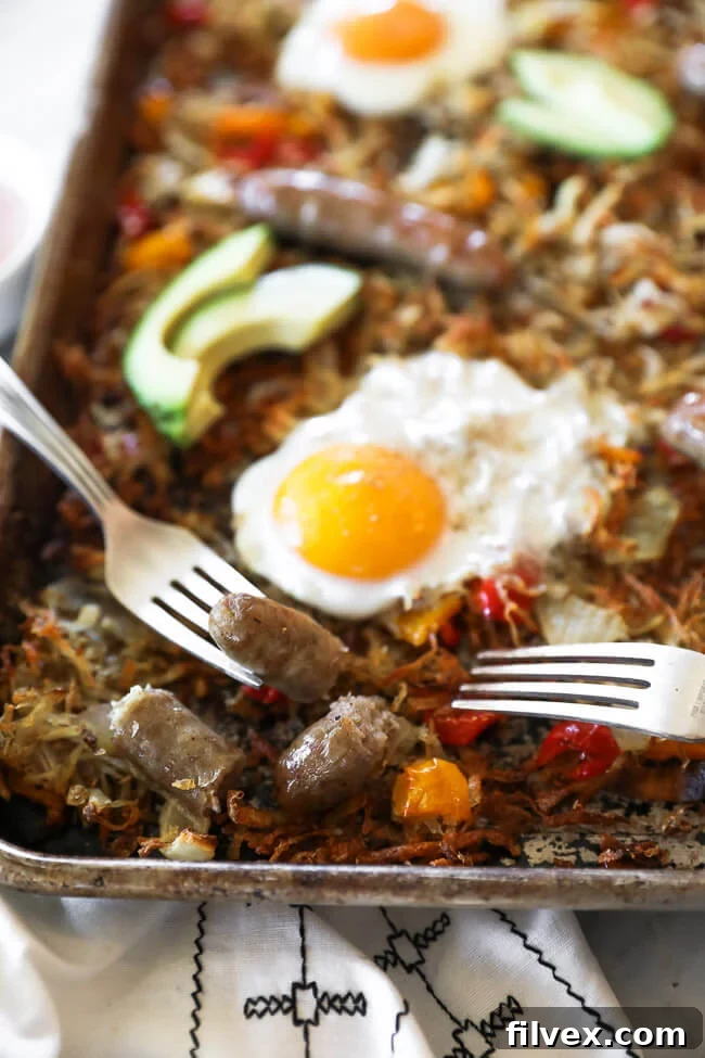 Close up angled shot of sheet pan breakfast bake with sausage cut up and a bite on one fork on the pan. 