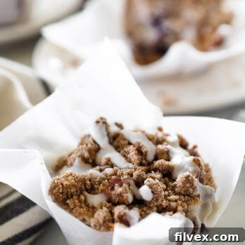 Close up vertical angled image of one coffee cake muffin with coconut butter drizzle on top.