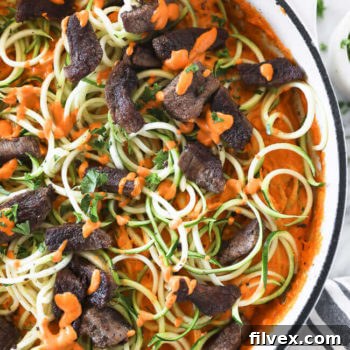 Roasted red pepper pasta with zucchini noodles and steak in a pan