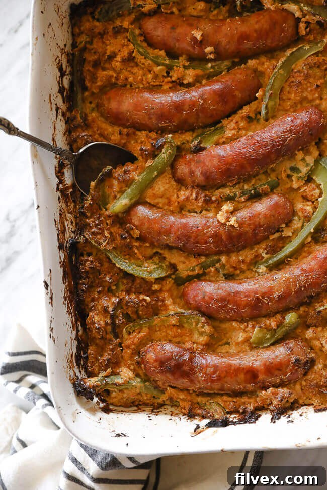 A close-up overhead vertical shot of the Italian Sausage Casserole, showcasing perfectly browned sausages and tender bell peppers resting on a creamy bed of cauliflower rice, rich with sauce.