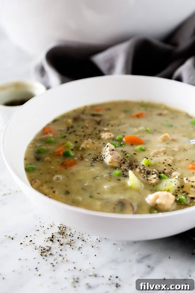 Vertical angled image of a bowl of chicken pot pie soup with extra ground pepper sprinkled on top. 