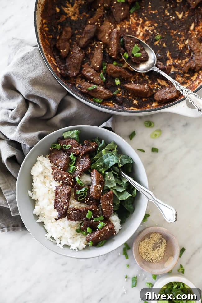 A bowl of Korean beef bulgogi served with vibrant kale and a side of rice, showcasing a healthy meal