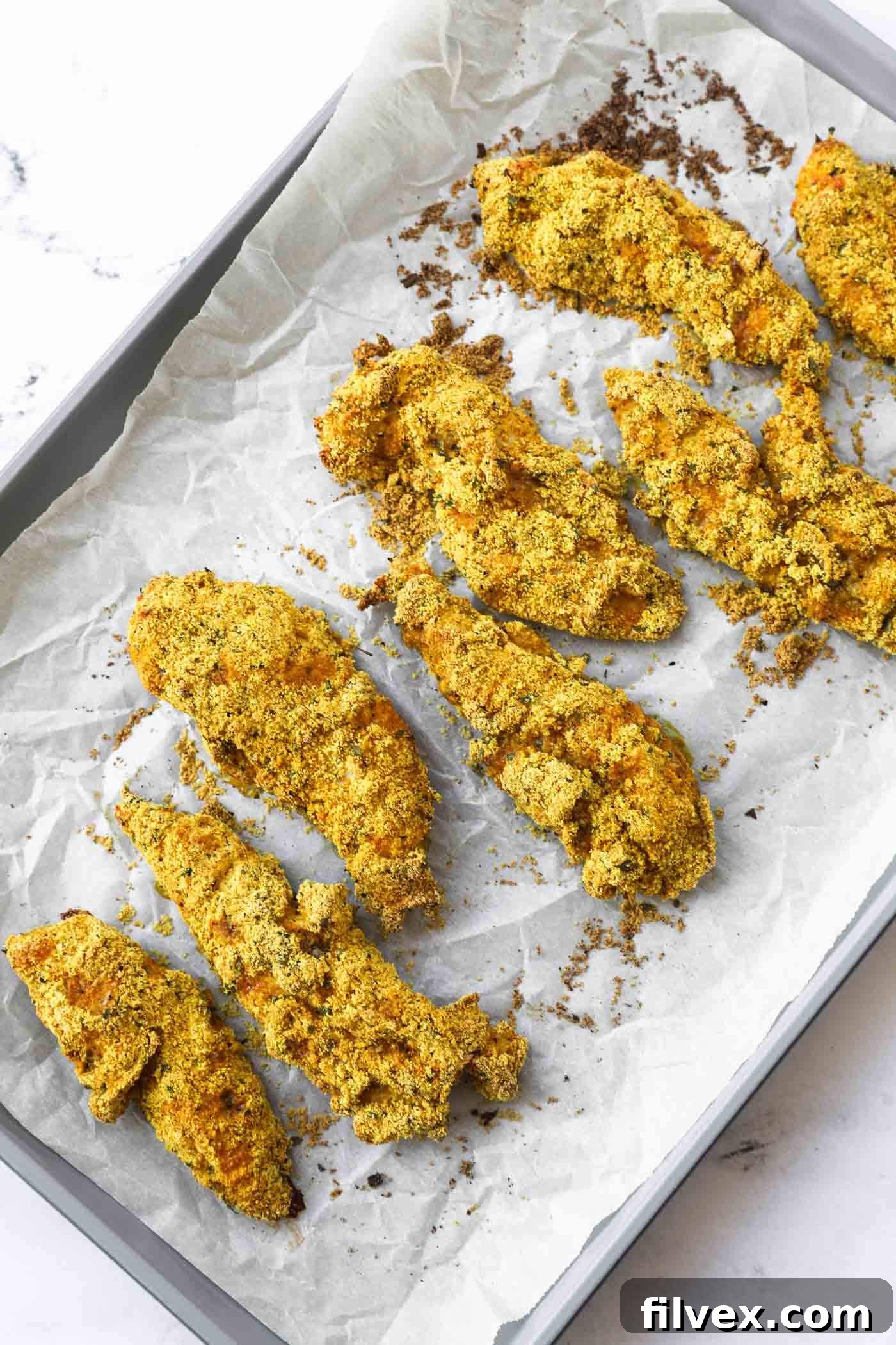 Golden brown baked almond flour chicken tenders on a baking sheet, ready to be served.