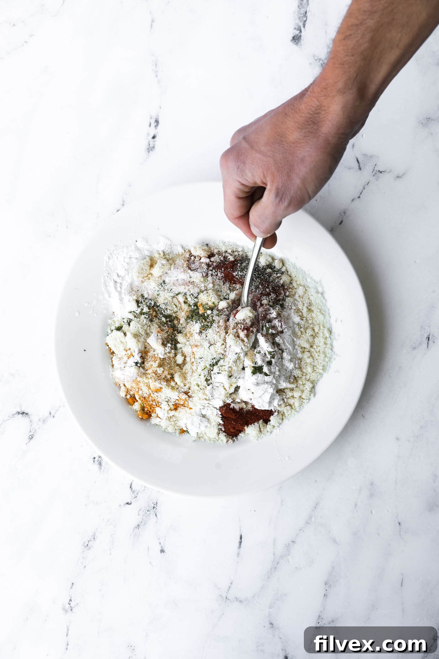 Almond flour and spices mixed together on a plate, ready for breading chicken.