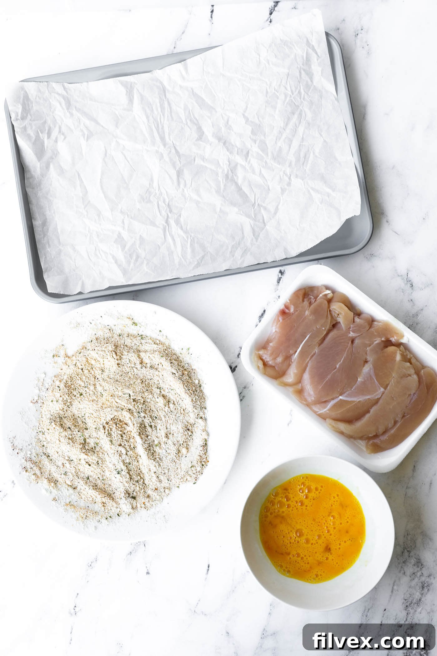All ingredients for chicken tender breading laid out for easy assembly line coating.