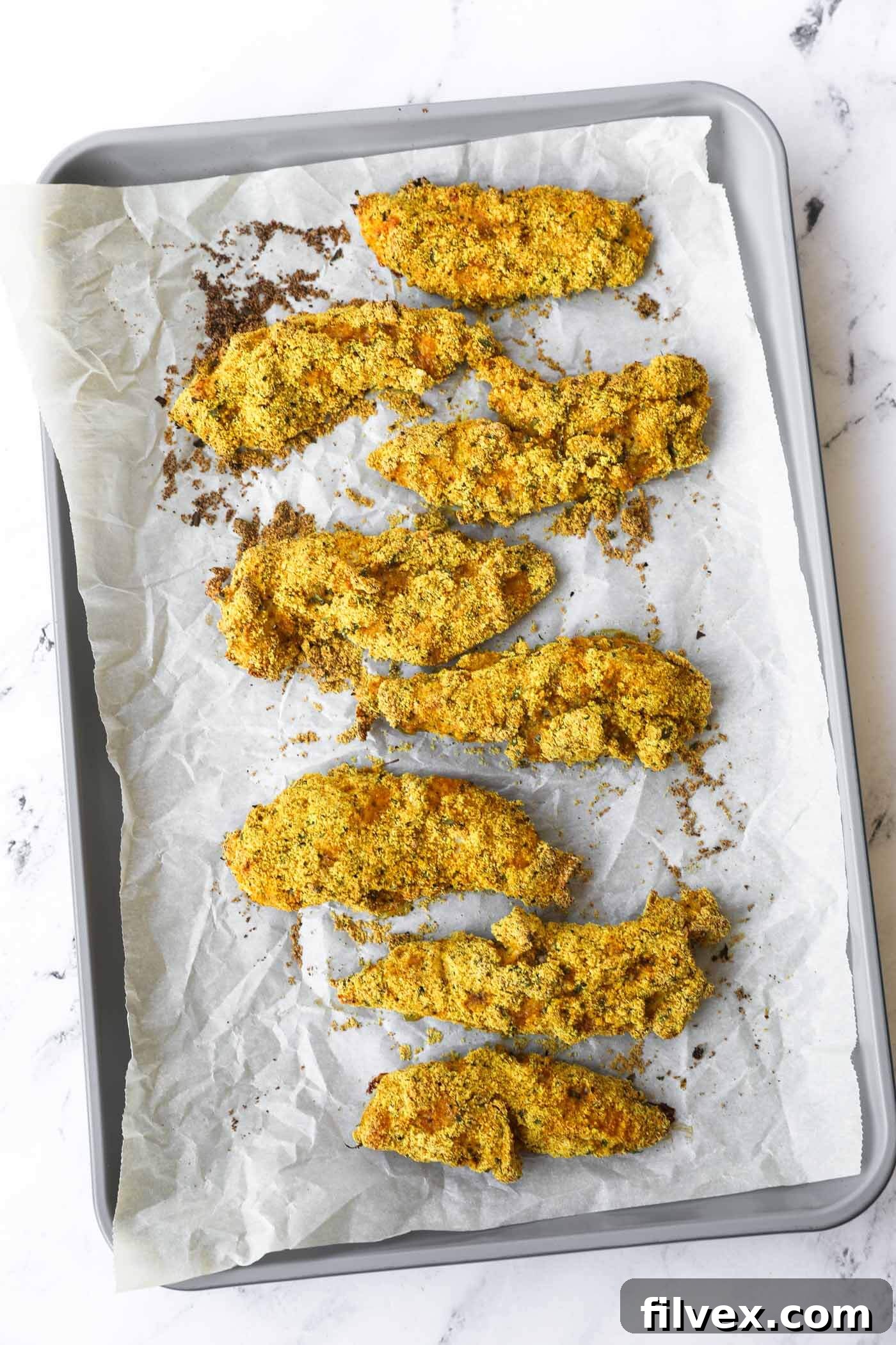 Baked chicken tenders fresh out of the oven, golden and crispy.