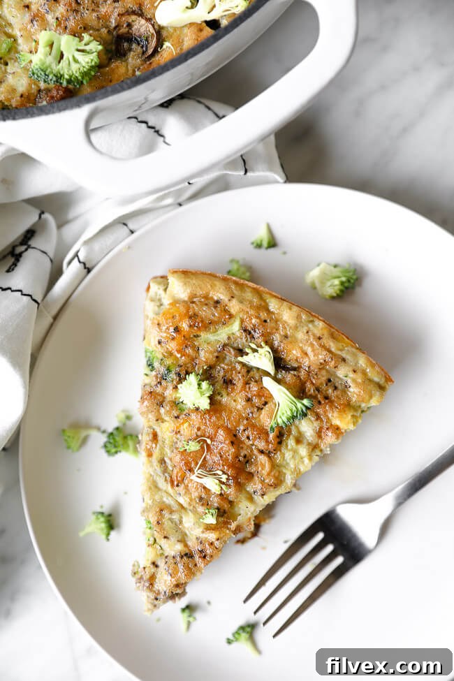 Vertical overhead image of one slice of Keto frittata served on a plate with a fork.