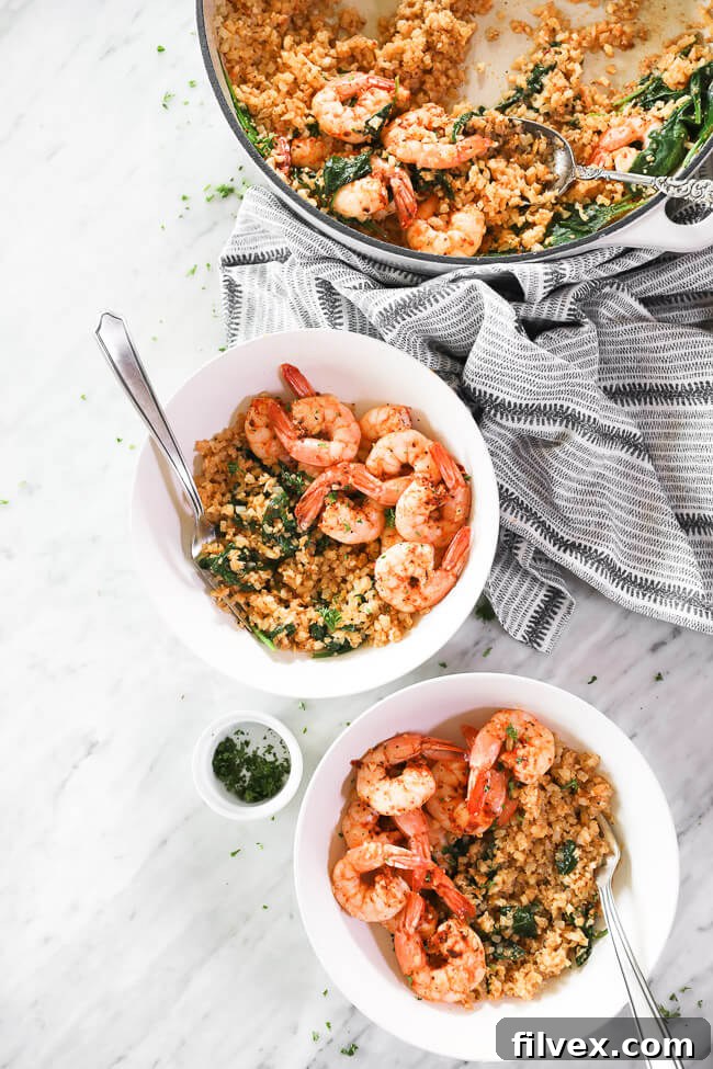 vertical overhead image of cajun shrimp and cauliflower rice in skillet and served up in two bowls with forks dug in. chopped parsley on the side. 