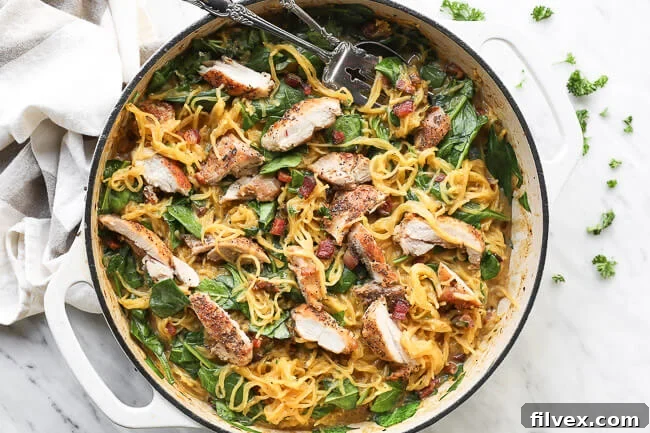 Horizontal overhead image of delicious, creamy spaghetti squash carbonara in a cast iron skillet with a serving fork and spoon dug in, showcasing the perfect texture and inviting presentation. 