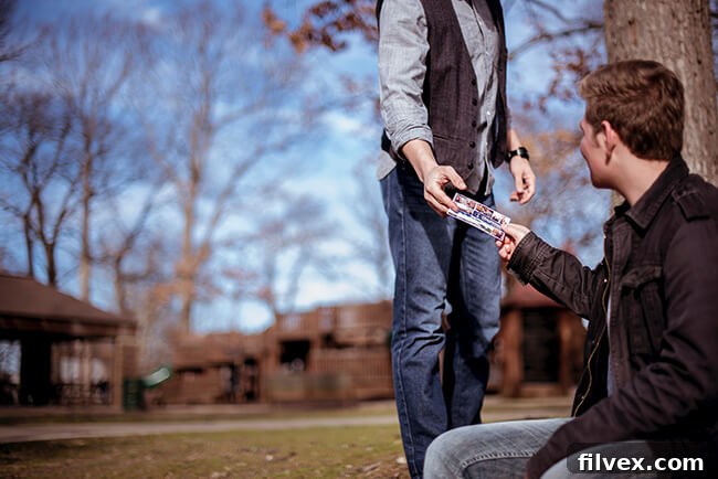 Man handing another man a postcard in a park