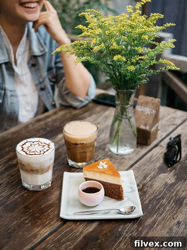 Woman smiling at table with flowers, coffee and a slice of cake