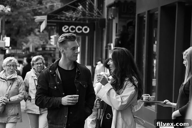 Man and woman on street with cups looking at each other