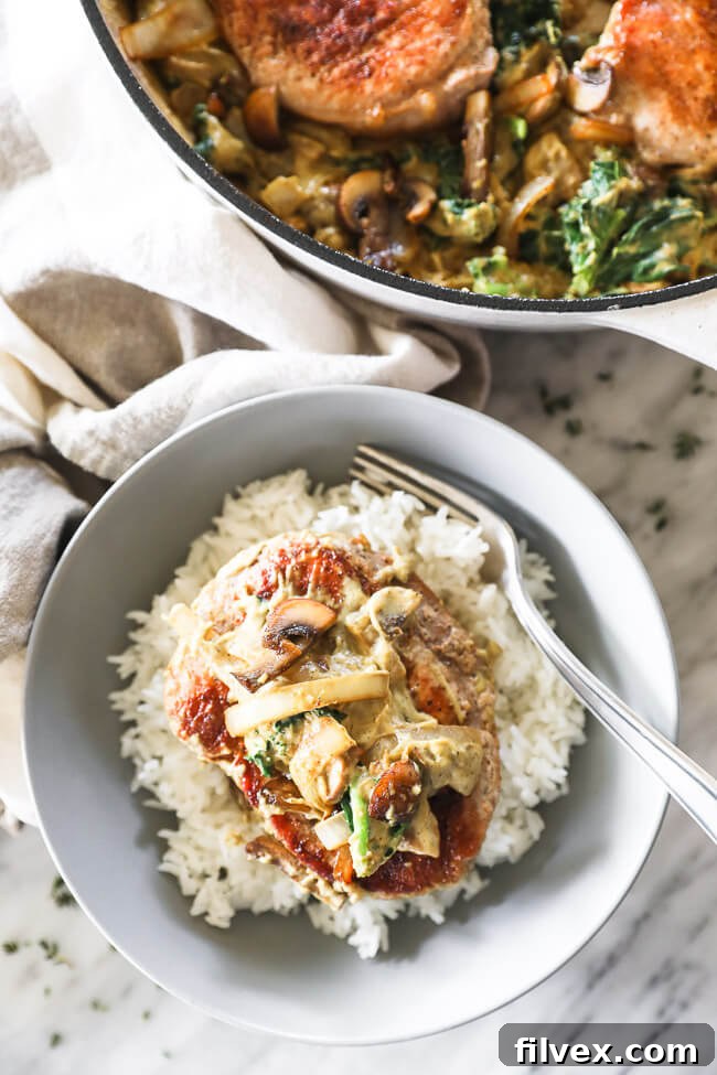 Vertical overhead image of creamy pork chops served in a bowl over white rice with a fork in the bowl.