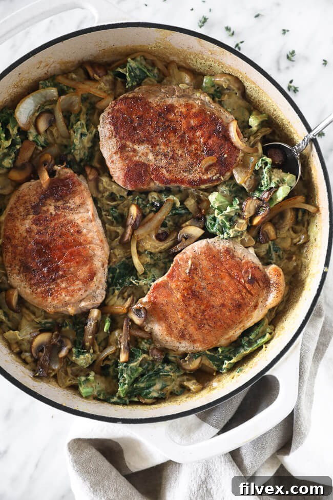 Vertical overhead image of pork chops in a creamy sauce in a skillet with a serving spoon.