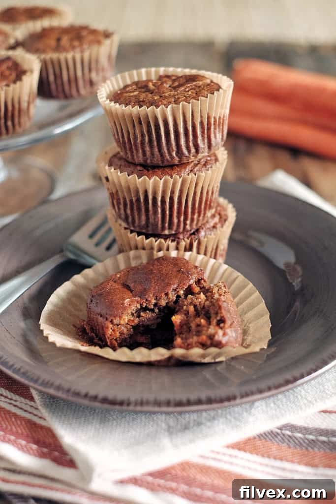 A single Paleo Carrot Cake Muffin, with visible grated carrot pieces and a tender crumb, ready to be enjoyed.