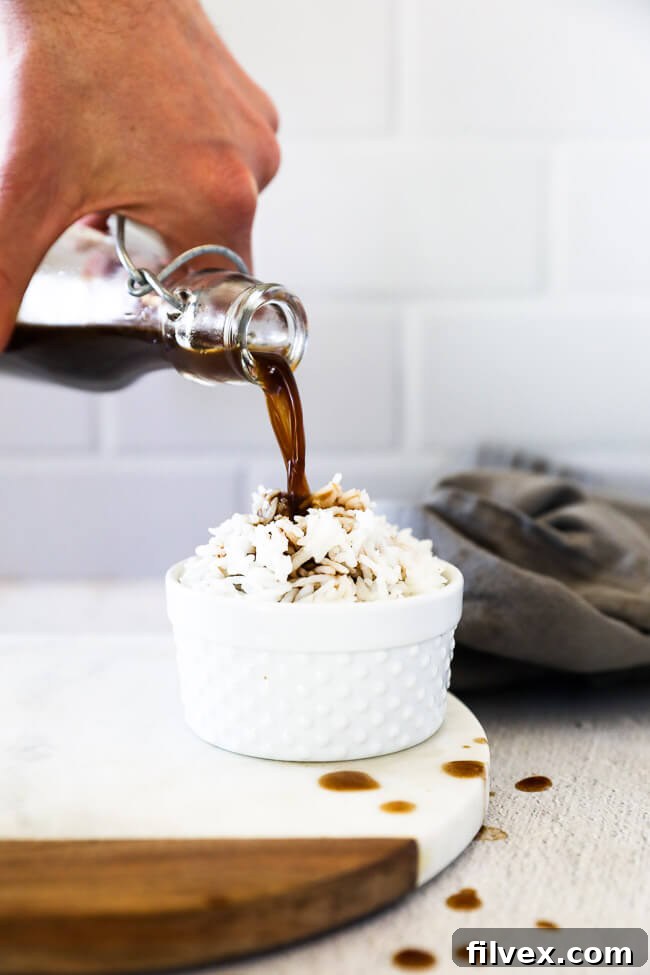 Coconut aminos substitute being poured over rice vertical image