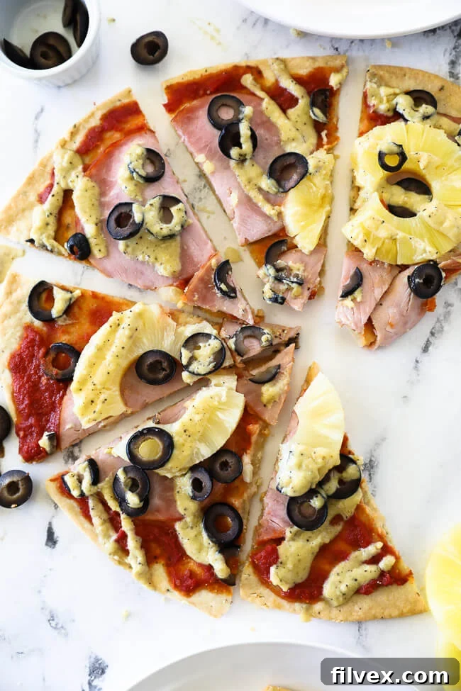 Overhead vertical image of hawaiian pizza sliced into pieces and spread out on marble.