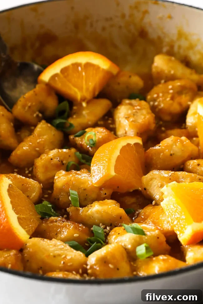 Healthy orange chicken in pan with orange slices close up vertical image