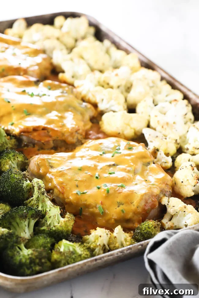 Angled image of honey mustard pork chops on a sheet pan with broccoli and cauliflower. 