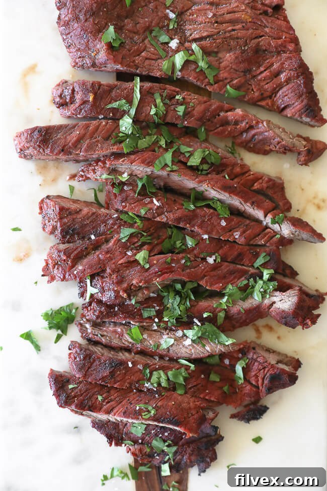 Perfectly grilled Carne Asada steak on a wooden cutting board, sliced into strips and garnished with fresh cilantro and a sprinkle of salt. Overhead vertical shot highlighting the delicious texture.