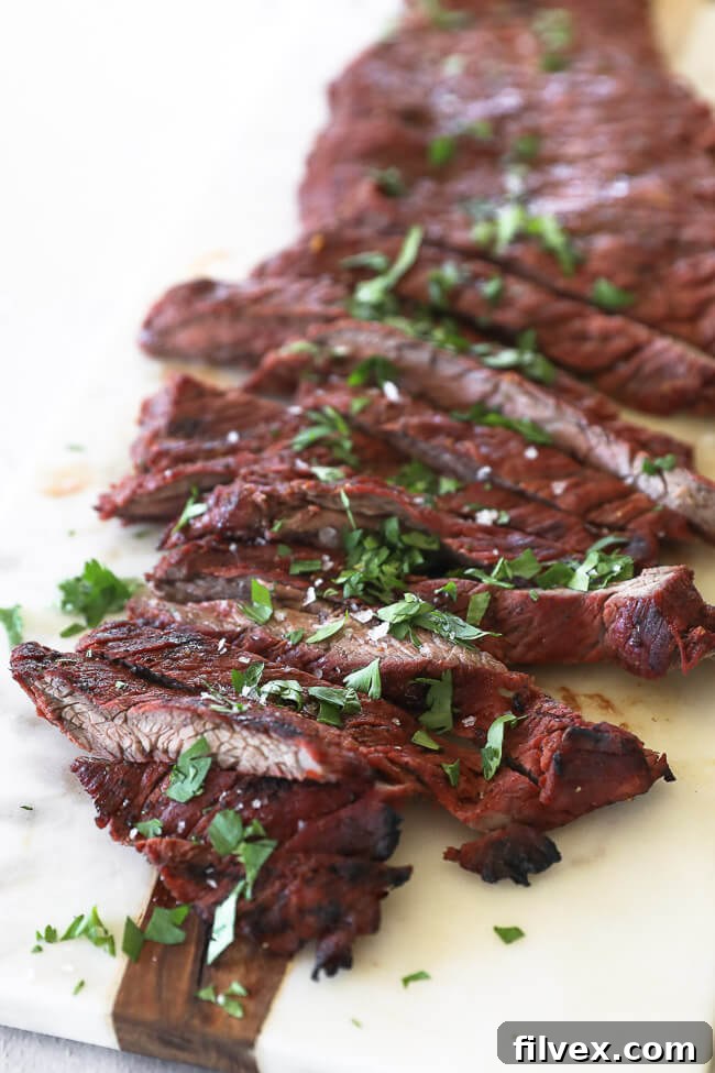 Close-up angled shot of quick and easy Carne Asada steak, sliced into tender strips and topped with fresh cilantro on a rustic cutting board, ready for serving.