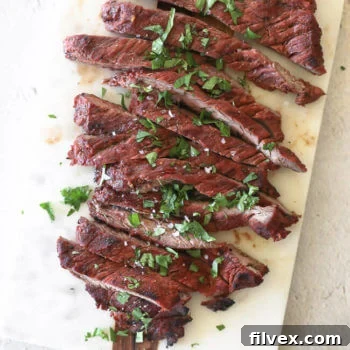 Grilled Carne Asada steak on a board, beautifully cut into strips and garnished with a sprinkle of salt and fresh cilantro, ready to be served.