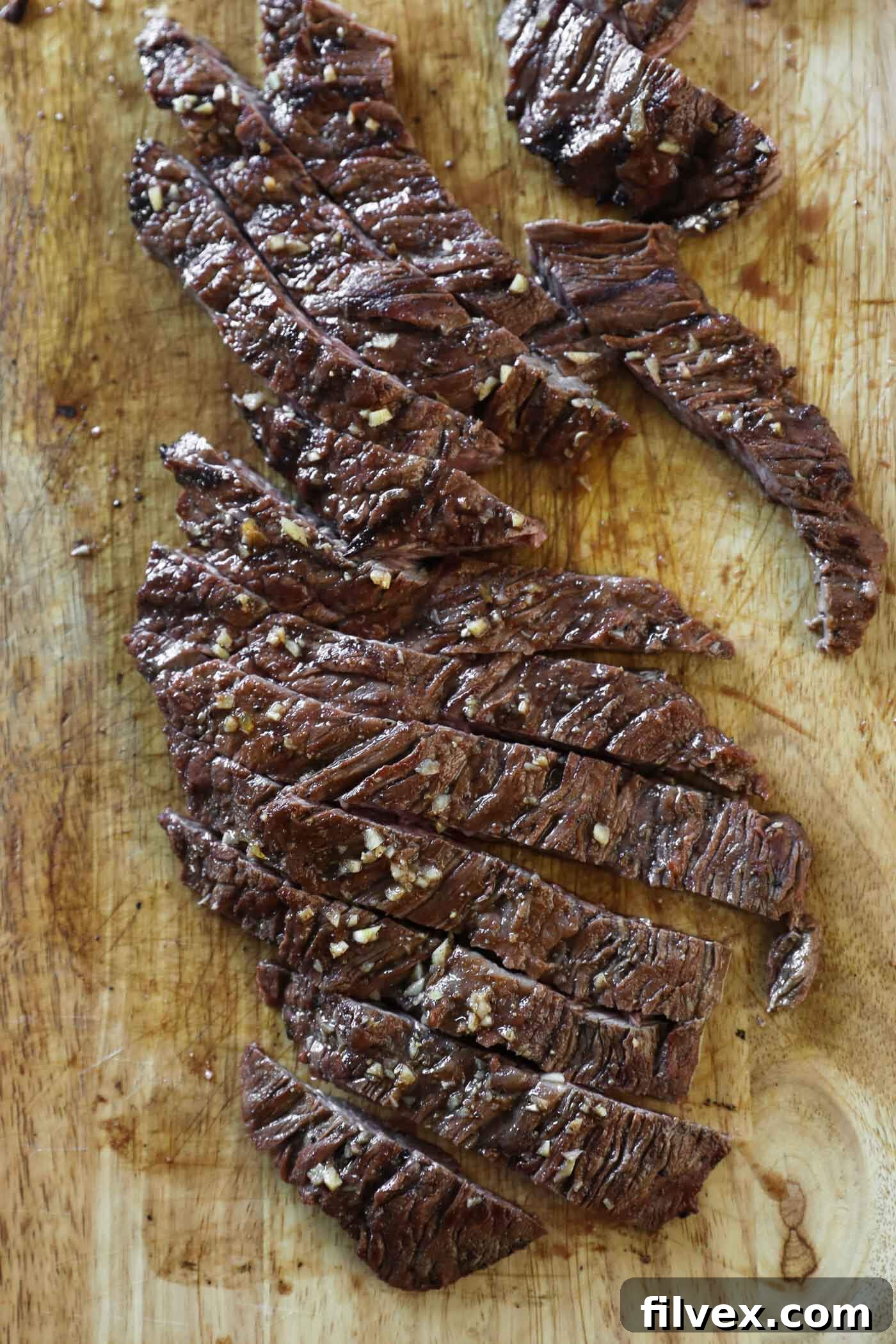 Close-up of perfectly sliced carne asada strips arranged on a cutting board, emphasizing the tender texture achieved by cutting against the grain.