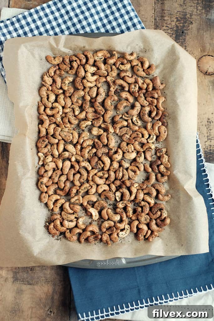 A close-up of golden-brown ranch roasted cashews, perfectly seasoned and scattered on a white surface, highlighting their appealing texture. Ideal for quick snacks or entertaining. | realsimplegood.com