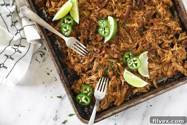 Close-up of shredded chicken carnitas in a rustic bowl, garnished with fresh cilantro and lime wedges.
