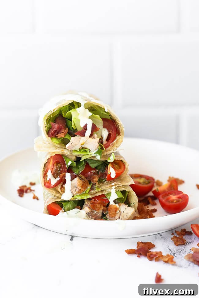 Stack of grilled chicken bacon ranch wraps cut in half on a plate with ranch dripping down, showcasing the delicious filling.