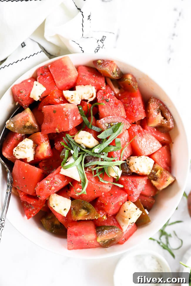 Close up image of tomato watermelon salad in a bowl with fresh chopped basil on top. 