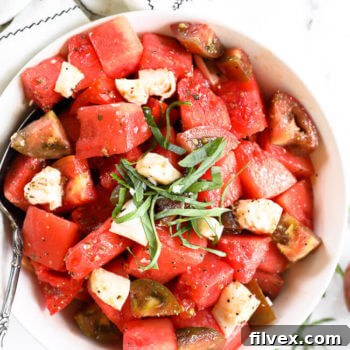 Close up image of tomato watermelon salad in a bowl with fresh chopped basil on top.