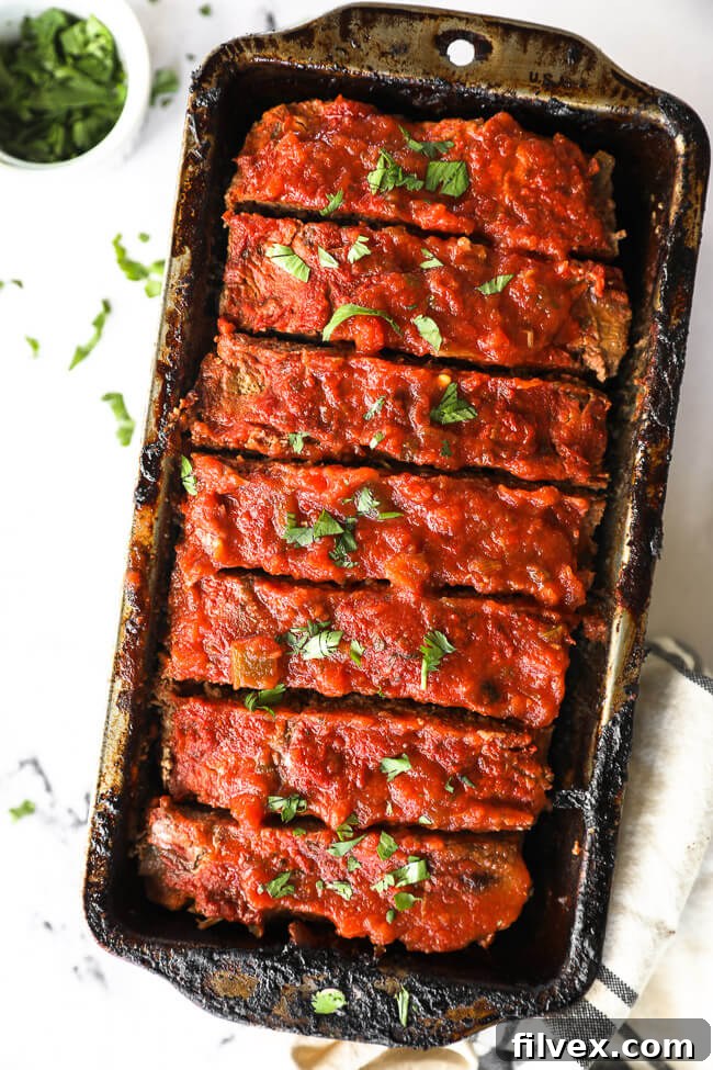 Taco meatloaf sliced in a pan with fresh cilantro topping, ready to serve.