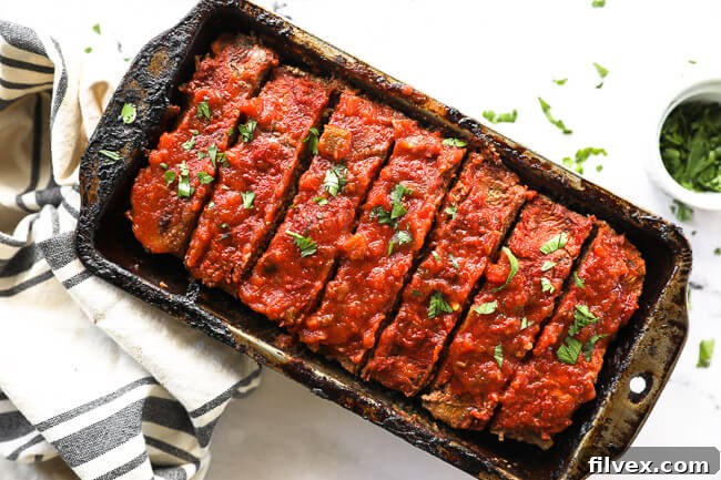 Horizontal image of taco meatloaf sliced in a pan with cilantro topping, showing its rich texture.