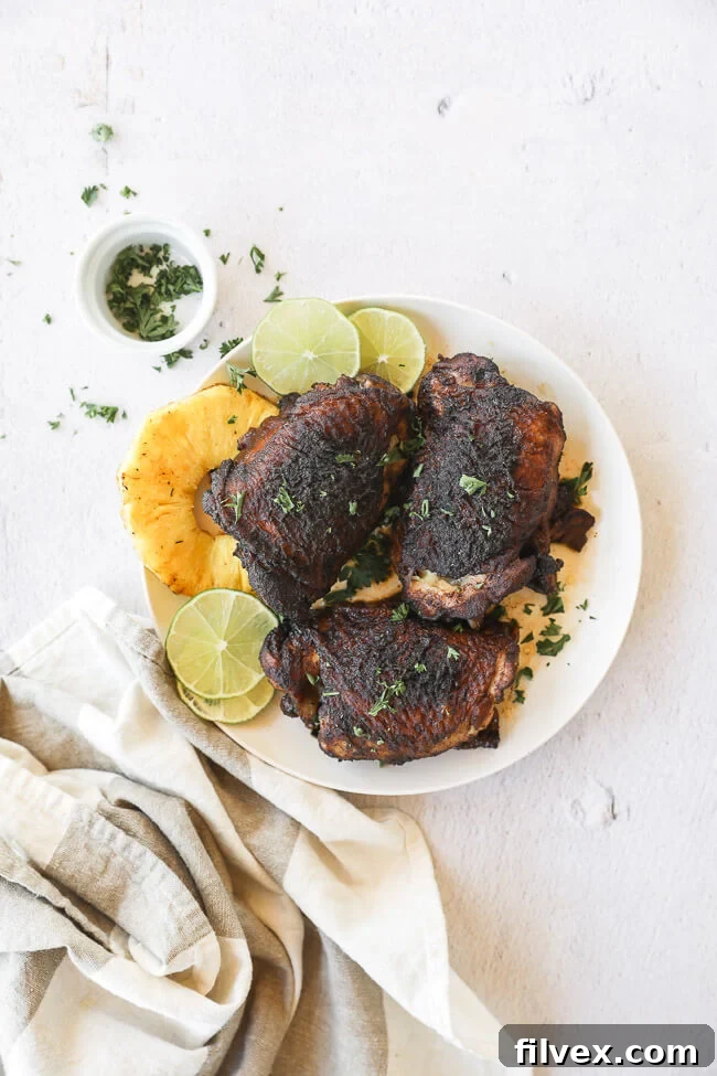 Close-up, vertical shot of slow cooker jerk chicken on a plate with pineapple and lime, pulled out from the main serving area.