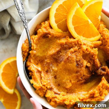 Mashed thanksgiving yams in a bowl with orange wedges