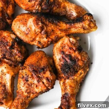 Overhead image of grilled chicken drumsticks on a plate with grill marks.