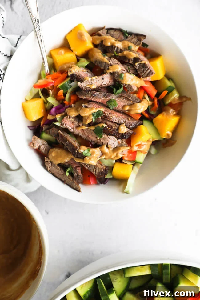 Close up of thai beef salad served in a bowl with cashew sauce drizzled on top.