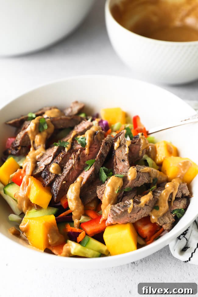 Angled close up image of thai beef salad in a bowl with cashew sauce drizzled on top.