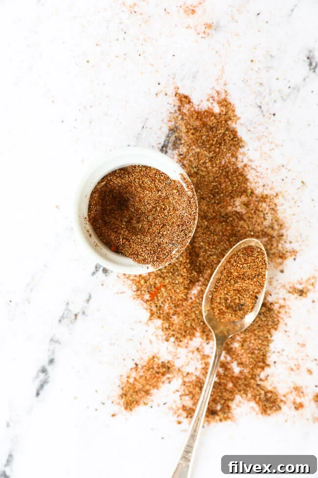 Taco seasoning in a ramekin with seasoning spilled out and spoon