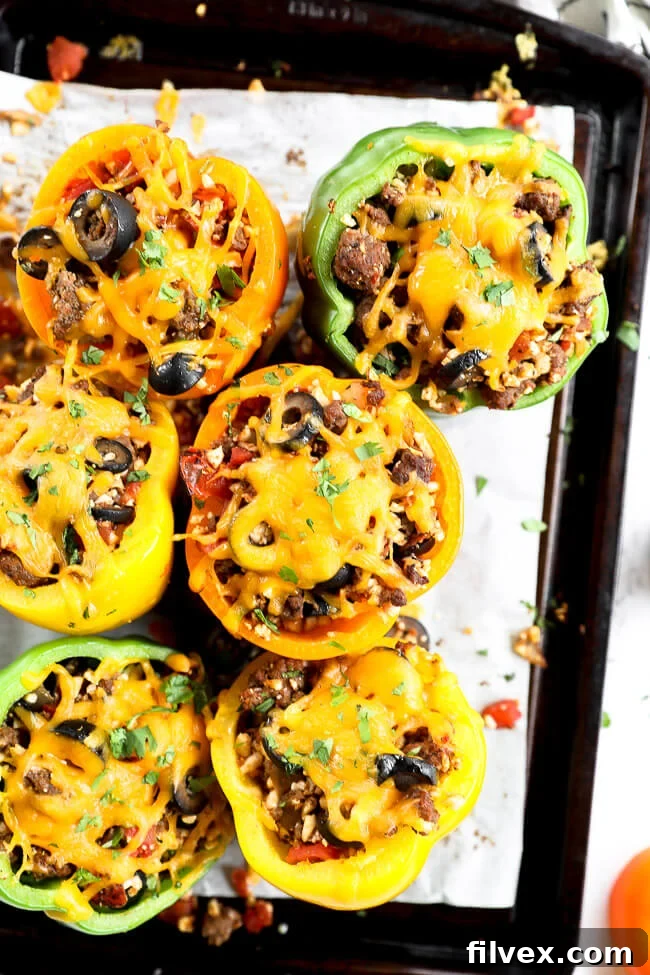 Stuffed bell peppers topped with melted cheddar cheese on a sheet pan