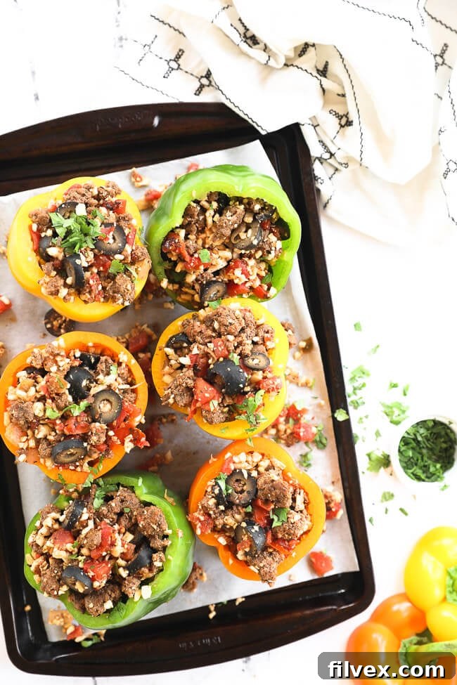 Stuffed bell peppers with ground beef and cauliflower rice on a sheet pan.