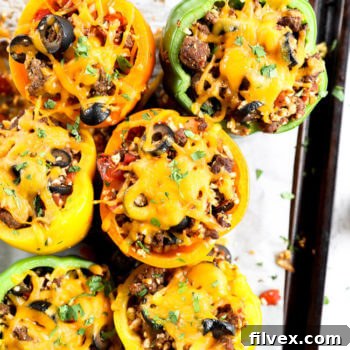 Stuffed bell peppers topped with melted cheddar cheese on a sheet pan