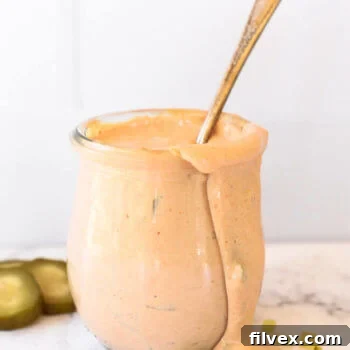 Keto Big Mac sauce in a jar with a spoon coming out, ready to be served. The sauce is creamy and rich, emphasizing its appeal for low-carb diets.