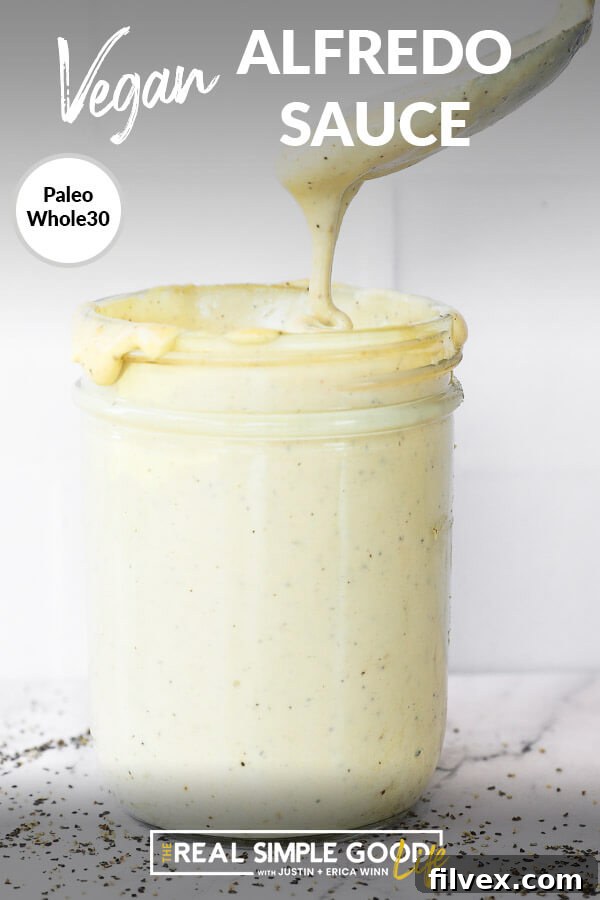 Vertical close up image of vegan alfredo sauce in a mason jar with a spoonful being pulled out. Text overlay at top of image. 