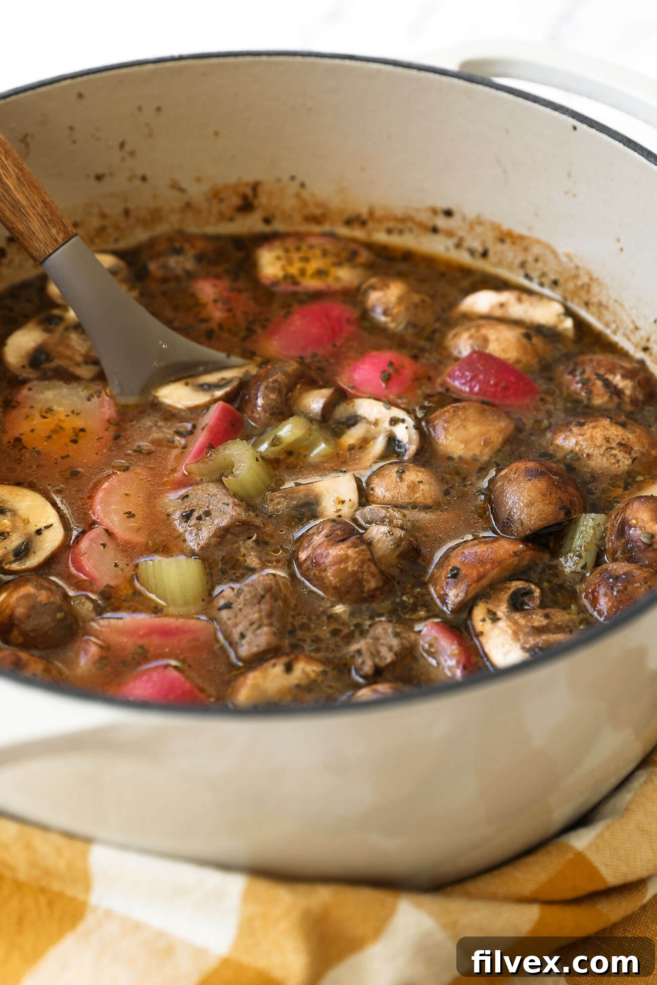 Hearty keto beef stew simmering in a Dutch oven on the stovetop, showcasing rich broth and vegetables