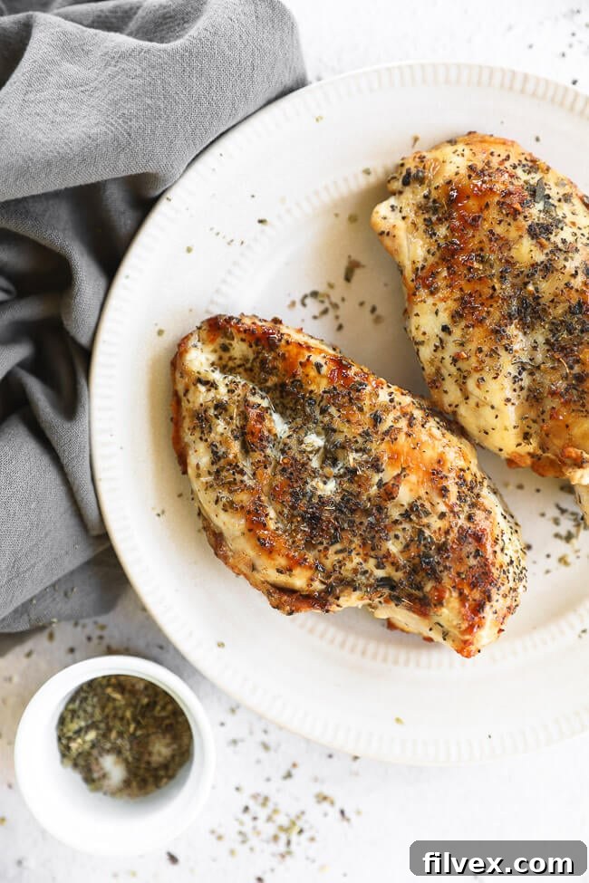 Cooked air fryer chicken breasts on a plate with seasonings