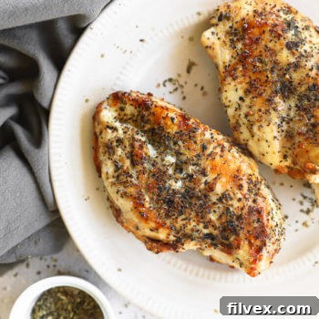 Cooked air fryer chicken breasts on a plate with seasonings