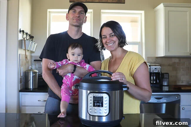 A family, Justin and Erica Winn, happily cooking in their kitchen with their baby and an Instant Pot Duo 6 Quart multi-cooker on the counter.