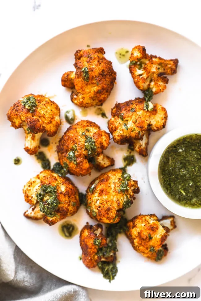 Crispy air fryer cauliflower on a white plate with a drizzle of vibrant green chimichurri sauce on top